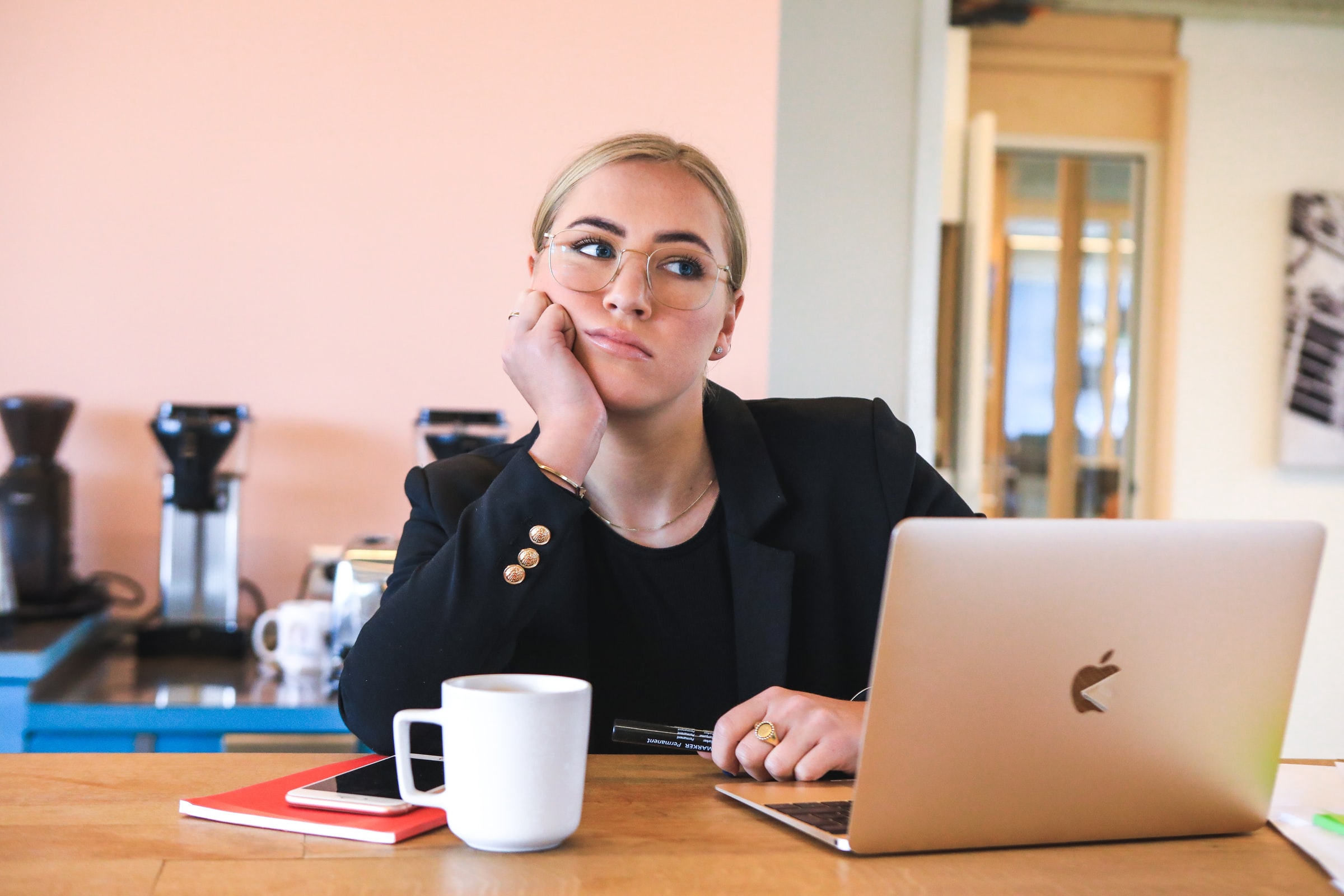 Distracted woman sitting at desk with laptop and coffee cup