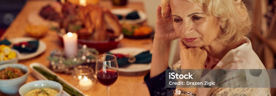 Sad mature woman feeling lonely and missing her family at dining table on Thanksgiving.