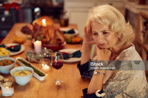 Sad mature woman feeling lonely and missing her family at dining table on Thanksgiving.