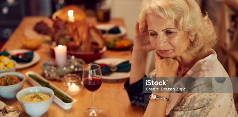 Sad mature woman feeling lonely and missing her family at dining table on Thanksgiving.