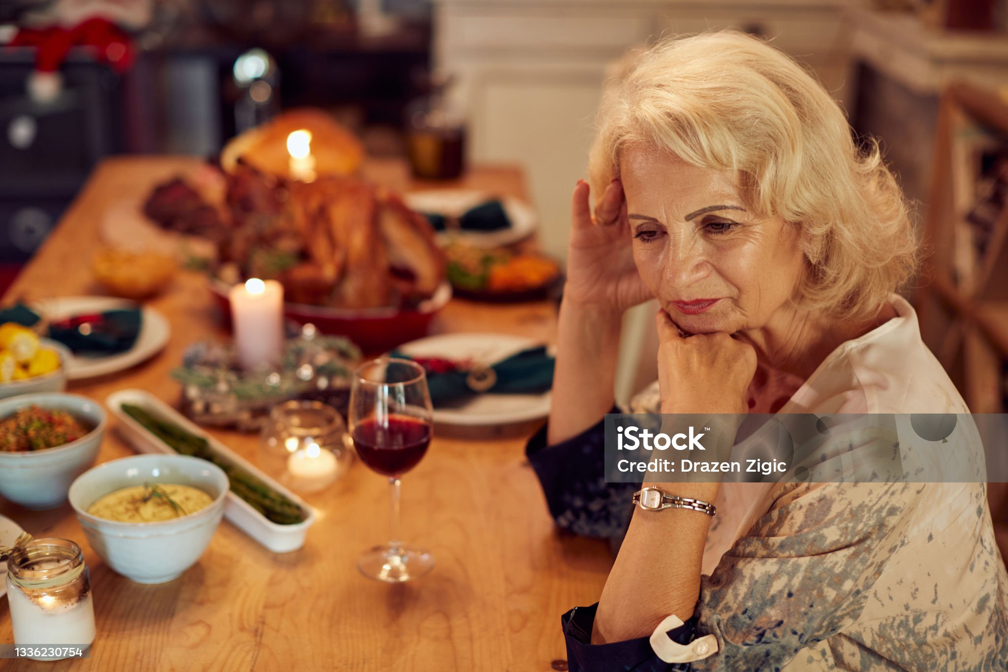 Sad mature woman feeling lonely and missing her family at dining table on Thanksgiving.