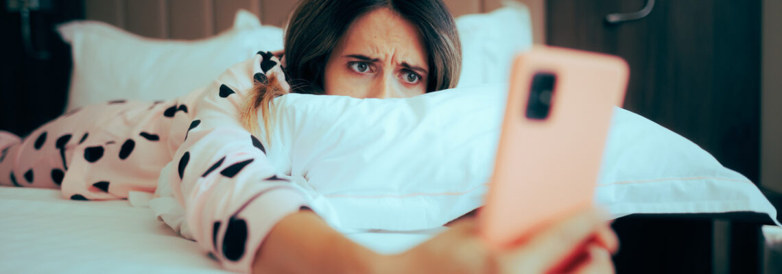 Worried Woman Looking at her phone Lying in Bed