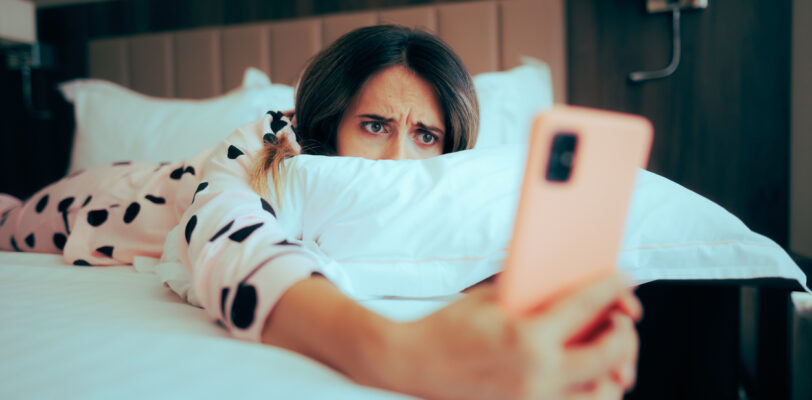 Worried Woman Looking at her phone Lying in Bed